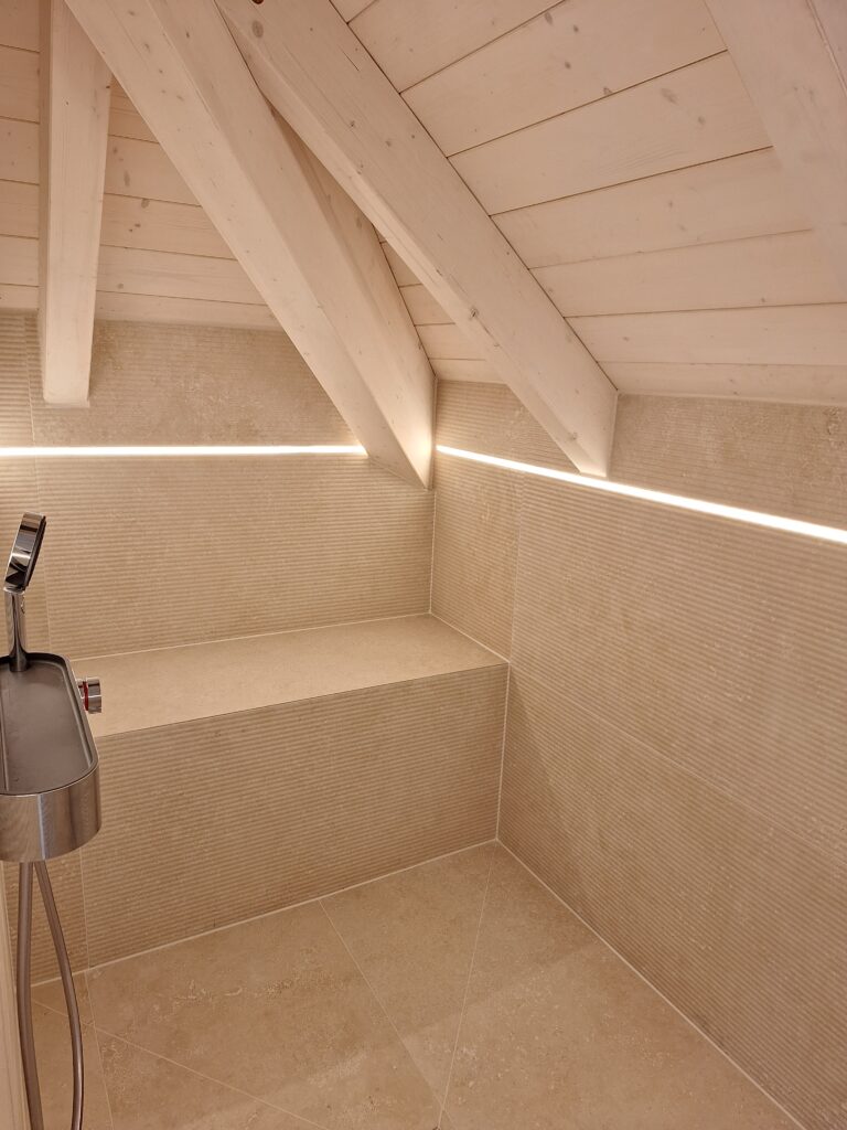 Dusche im Dachgeschoss mit Rillenfliesen, Sitzbank und Lichtband