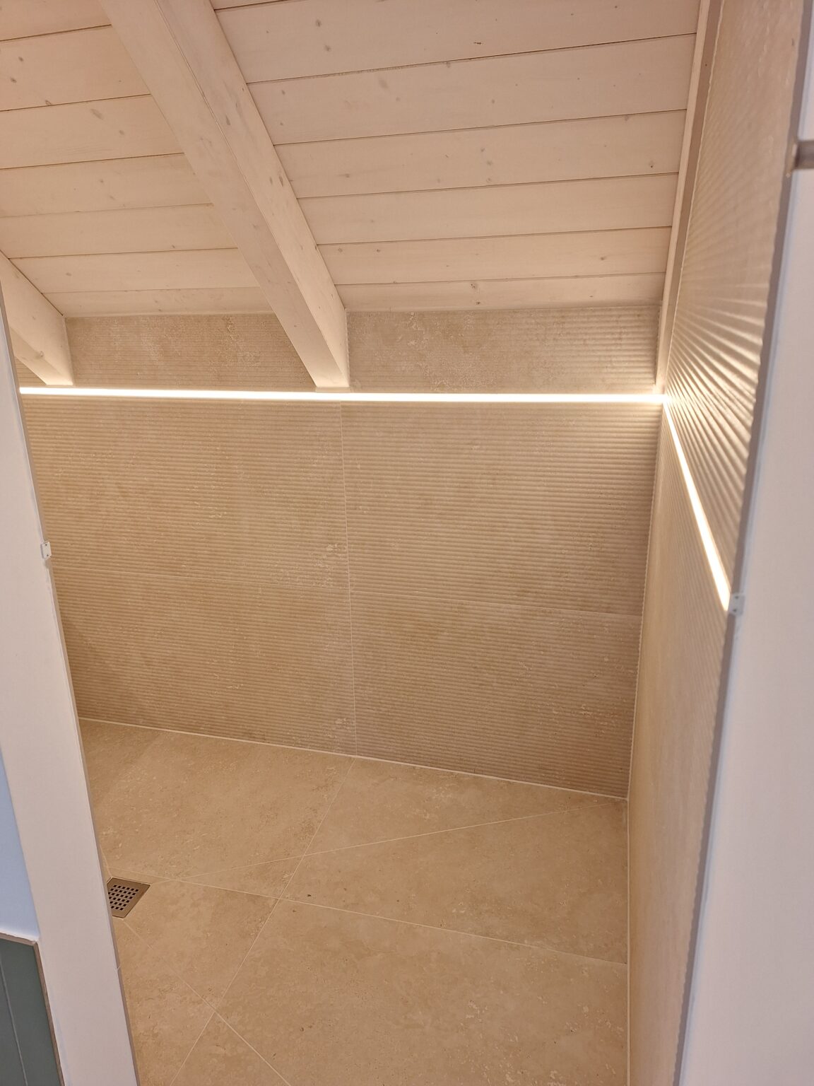 Dusche im Dachgeschoss mit Wandfliesen in Rillenstruktur und indirektem Lichtband